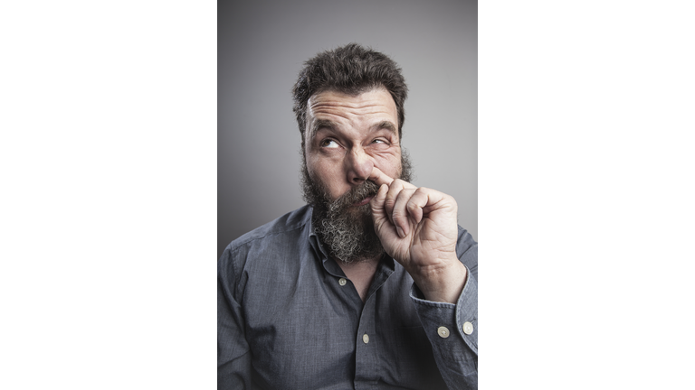 Portait of a mature man with full beard, picking his nose