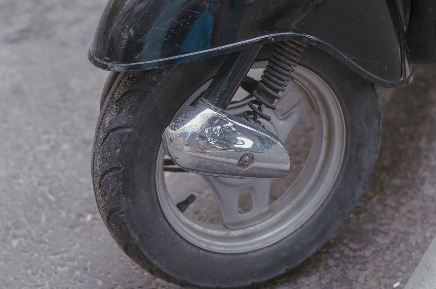 Wheel of a modern moped or minibike in a street parking lot.