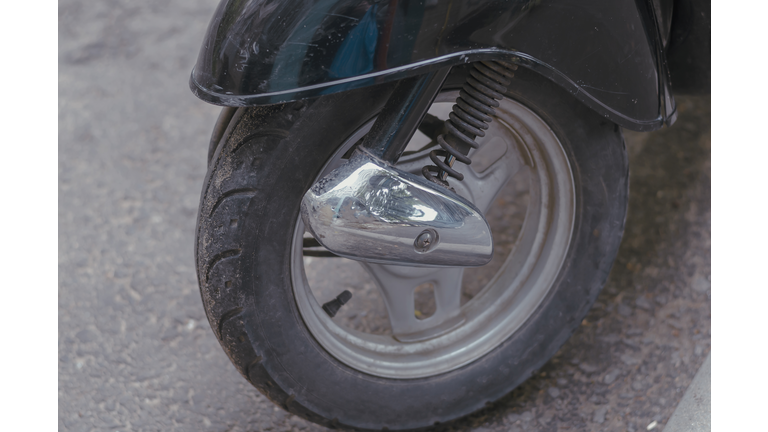Wheel of a modern moped or minibike in a street parking lot.