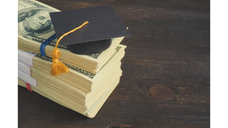 Savings for education and university concept. Stack of cash and graduation cap.