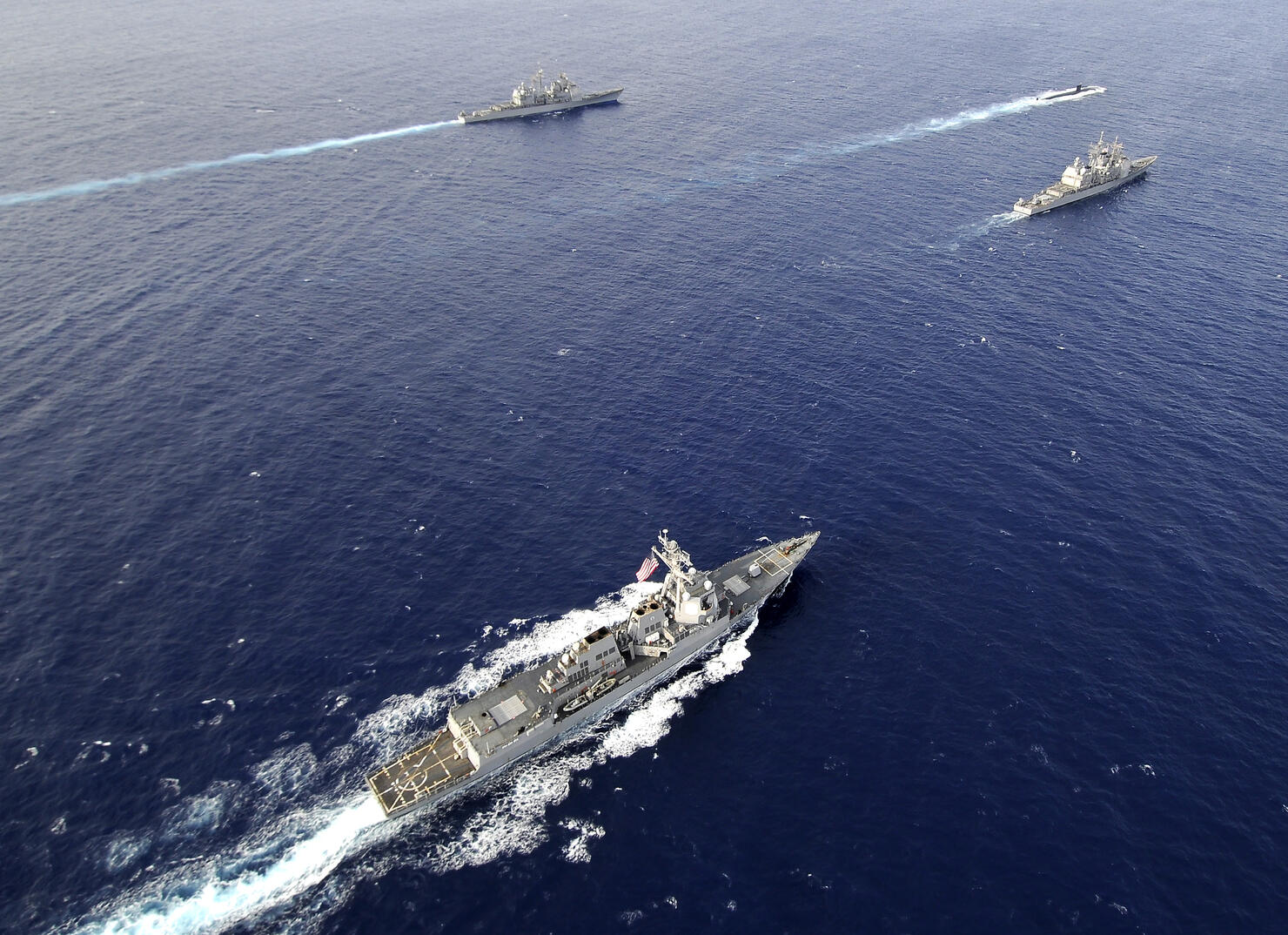 Aerial view of a naval fleet transiting the Pacific Ocean.