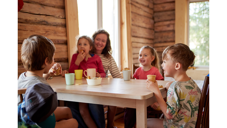 Family at the table eats ice cream and the children laugh