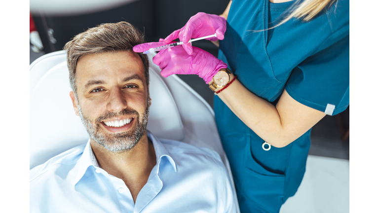 Applying beauty injection for handsome bearded man in beauty salon