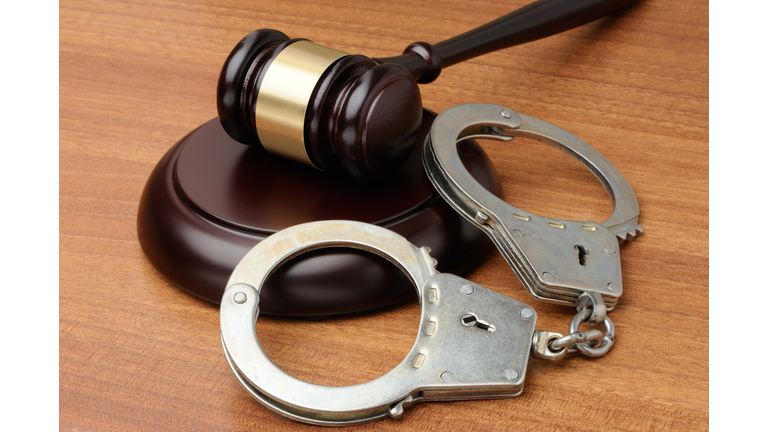 Handcuffs with gavel on a wood background