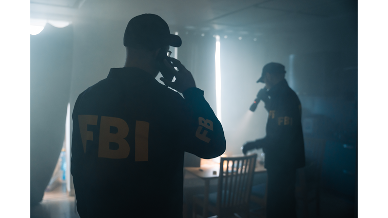 Action movie scene with two FBI agents at the crime scene in a fogged room of criminal's apartment, calling criminologists