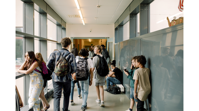 Rear view of students walking in school corridor