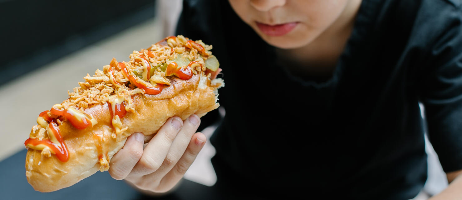 Caucasian boy 8-9 years eating a hot dog