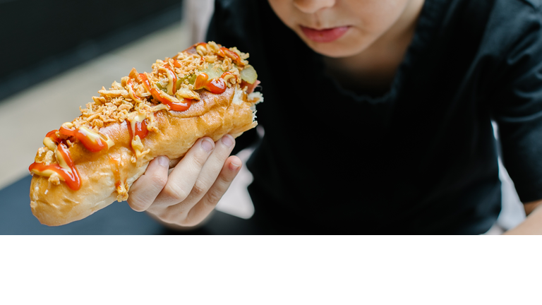Caucasian boy 8-9 years eating a hot dog