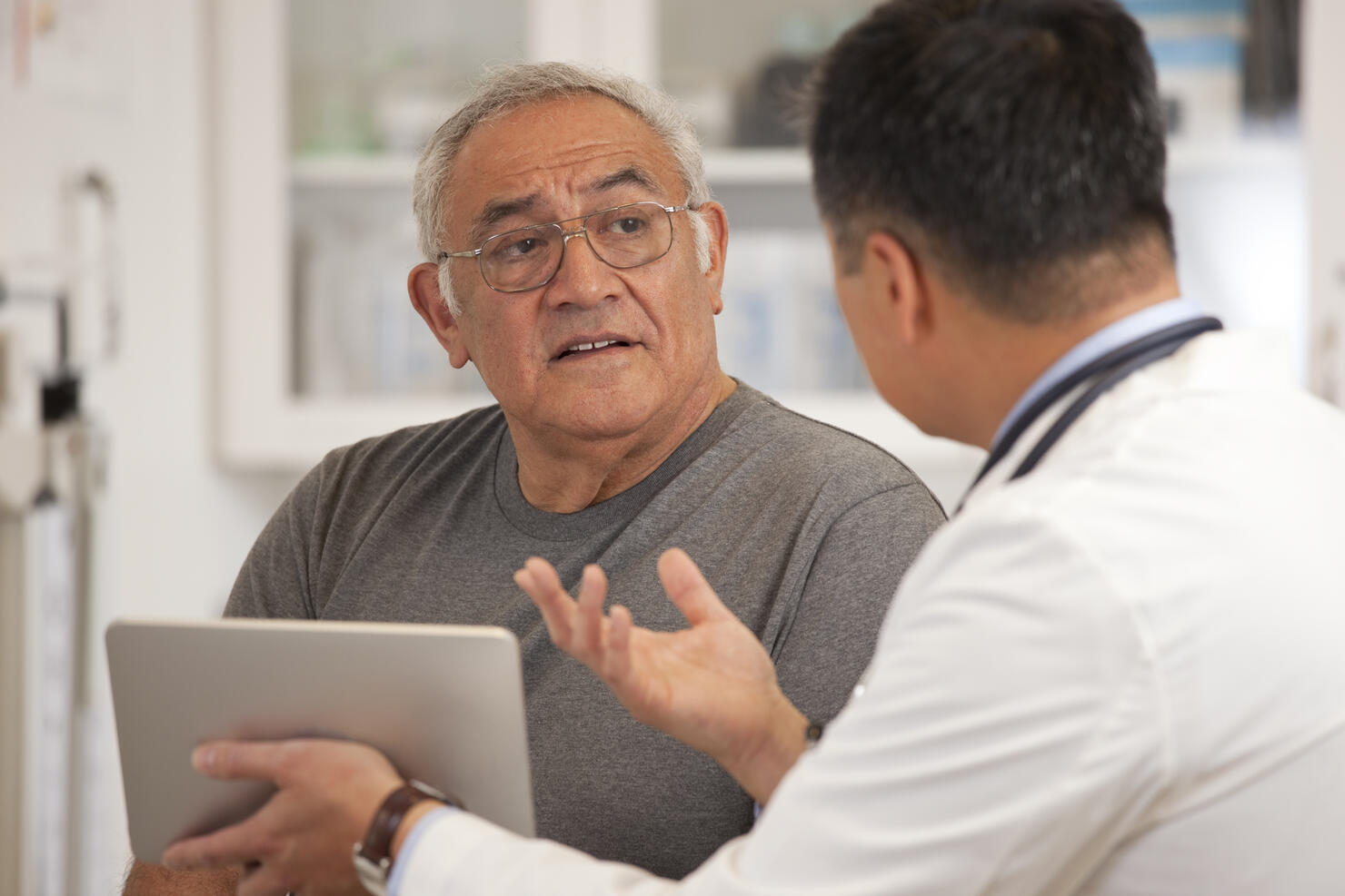 Doctor using digital tablet to talk to senior man