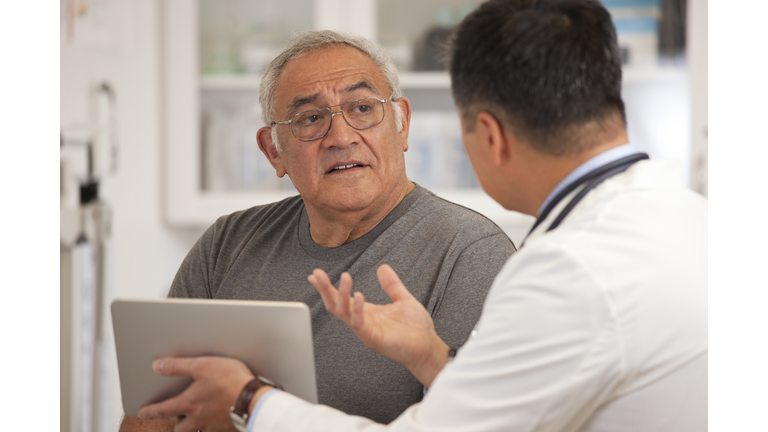 Doctor using digital tablet to talk to senior man