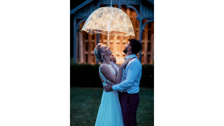 young wedding couple dancing under the fairy umbrella at night