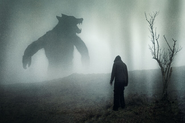 A horror concept of a man looking at a giant werewolf figure on a moody mountain side. With a grunge edit