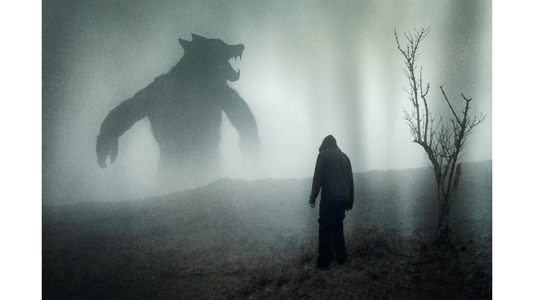 A horror concept of a man looking at a giant werewolf figure on a moody mountain side. With a grunge edit