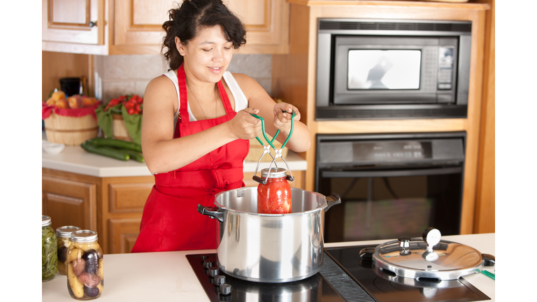 Woman canning tomatoes in her kitchen