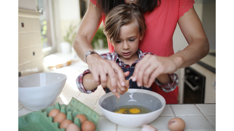 A 4 years old boy cooking at home with his mum
