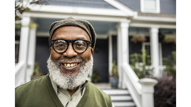 Portrait of senior man in front of suburban home