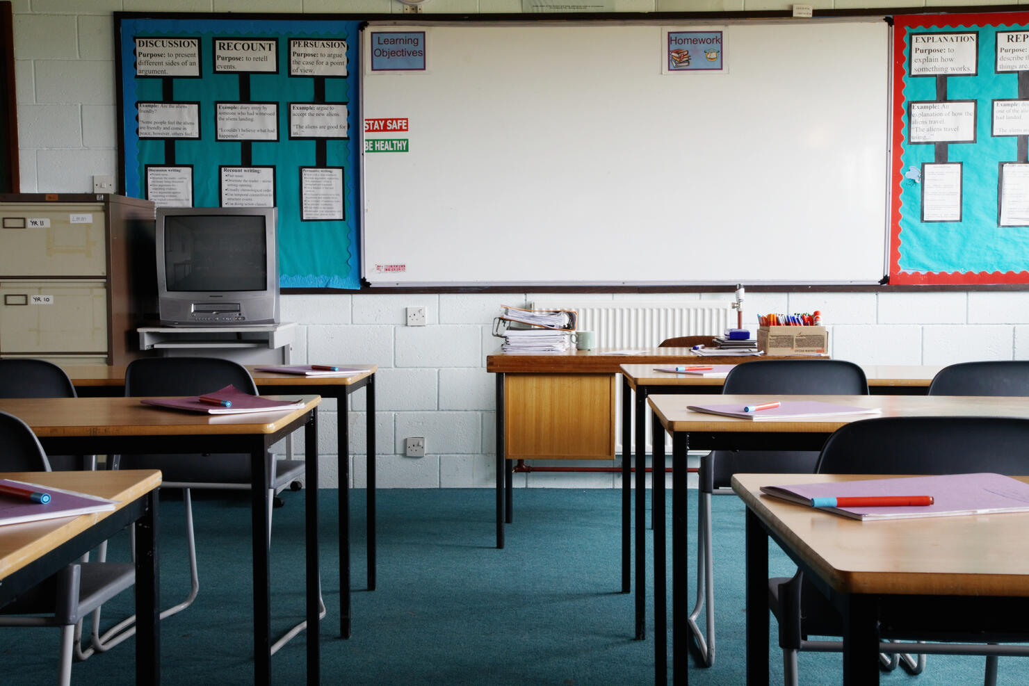 Empty school classroom, exercise books and pens on table