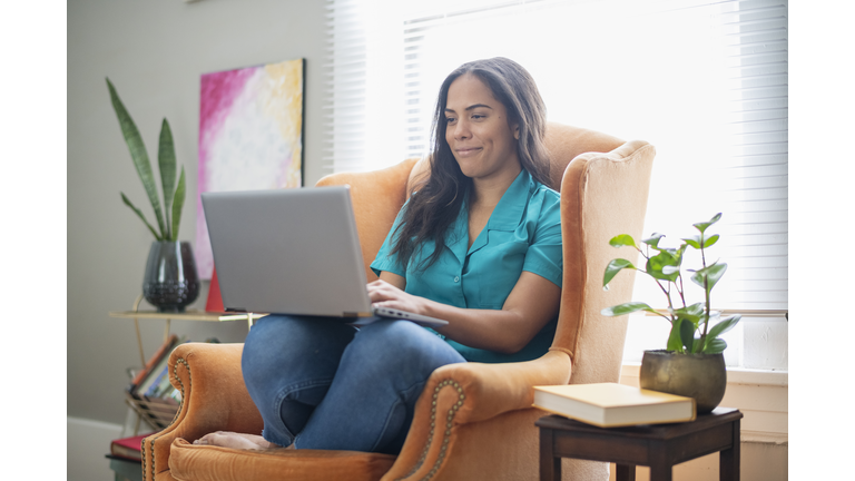 Woman in armchair at home using a laptop