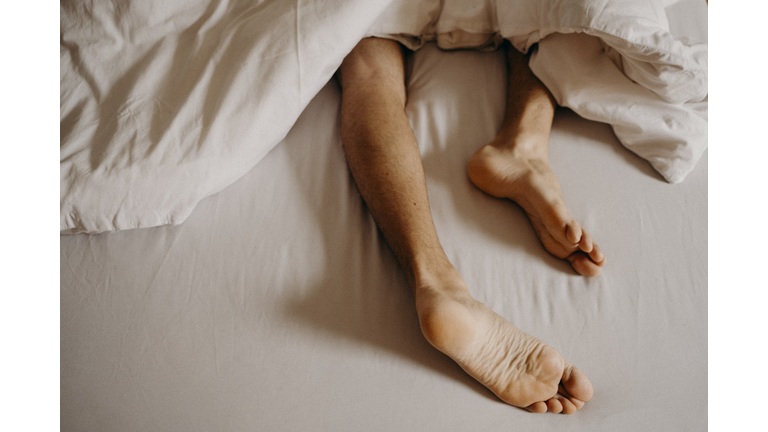 Man´s feet resting in bed