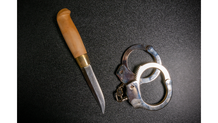 Handcuffs and knife on a black table. Violence, murder, street gang concept. Top veiw