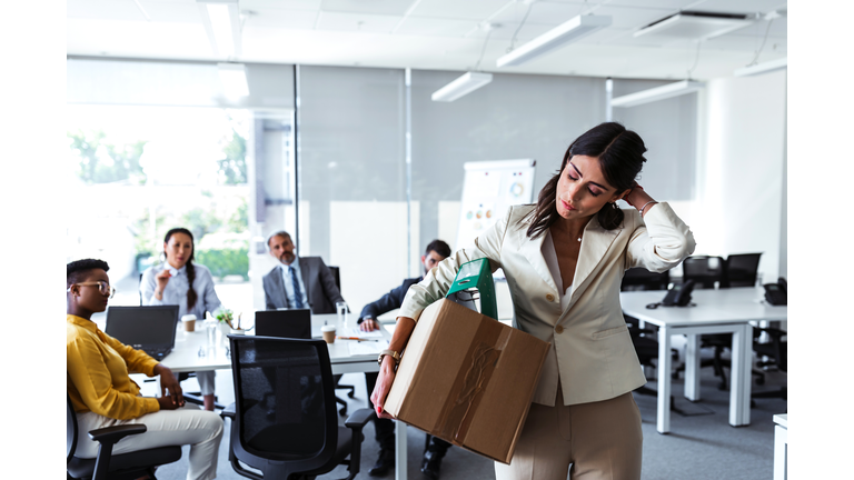 Mid adult businesswoman with cardboard box being fired