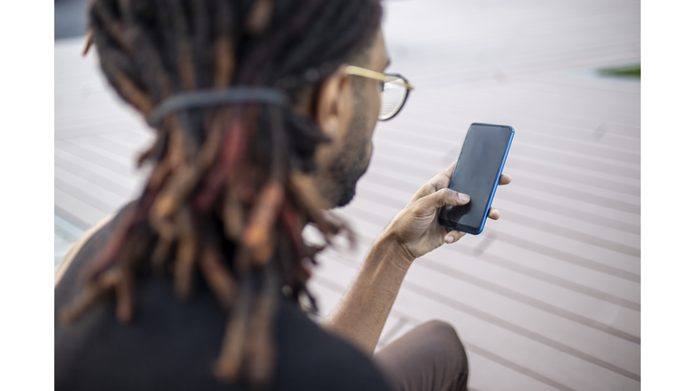 Young black cheerful man texting a message