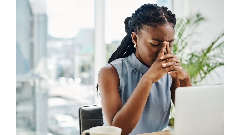 Stressed black businesswoman working on a laptop in an office alone