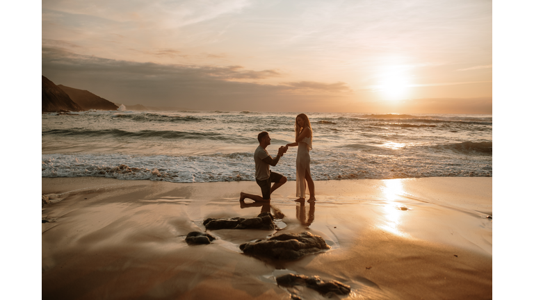 Young man proposing to his girlfriend at a beach