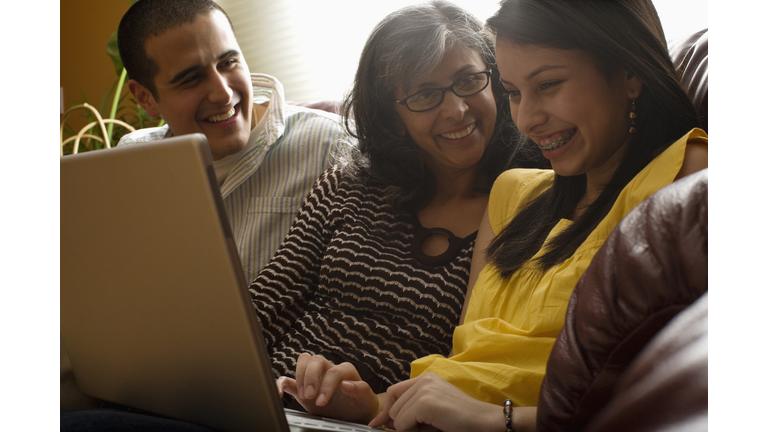 family laughing using laptop