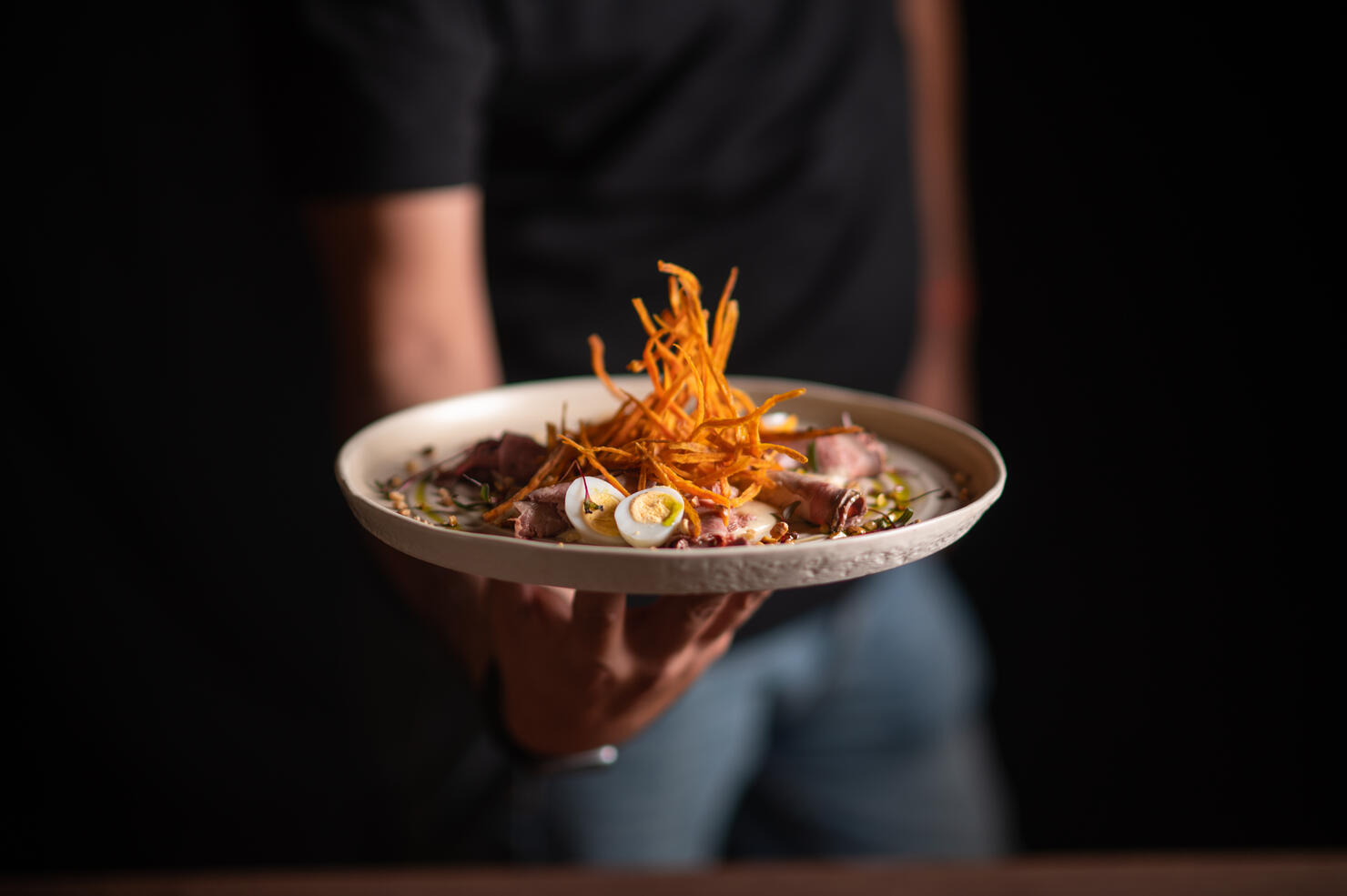 A male chef serving a fine dining dish in a restaurant