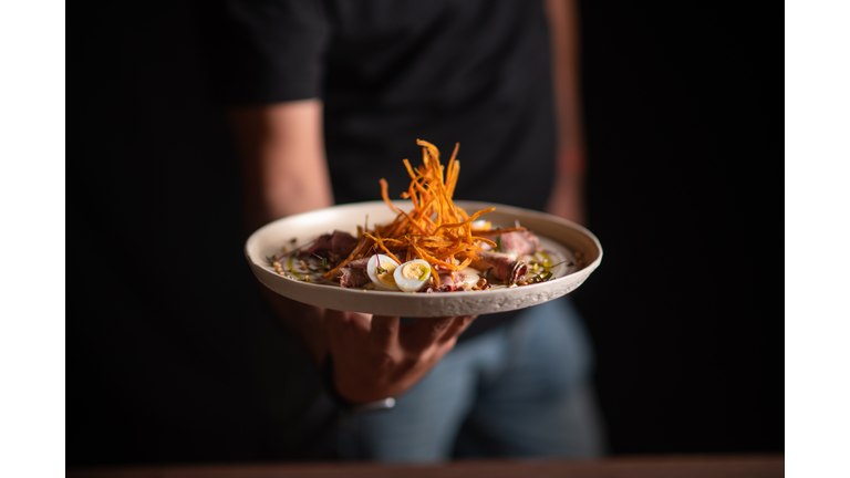 A male chef serving a fine dining dish in a restaurant