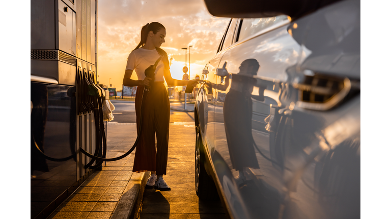 Young woman refueling her car at gas station