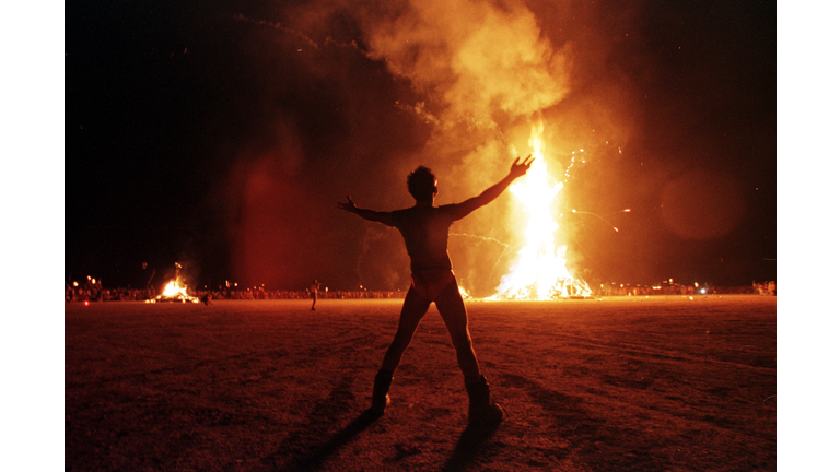 A "Burning Man" participant holds up his arms as t