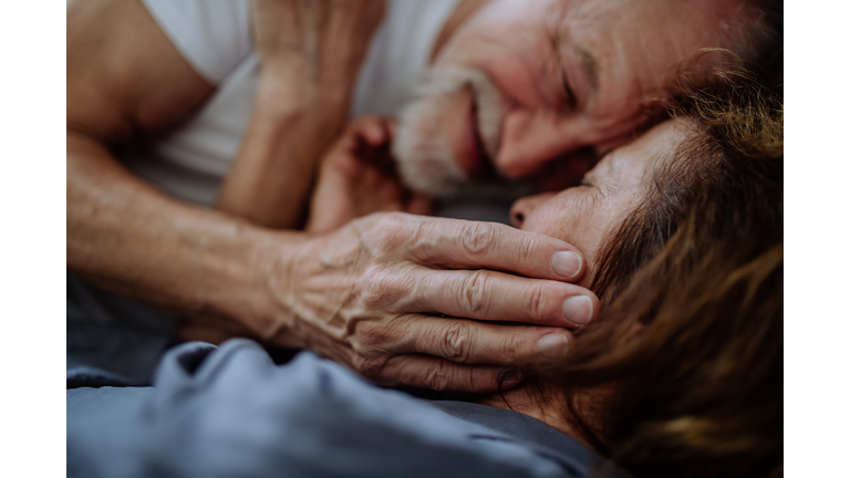 Close-up of senior couple lying together in bed. Concept of long lasting love.