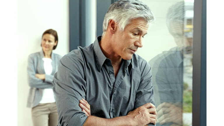 Portrait of unhappy man with his his wife standing in the background