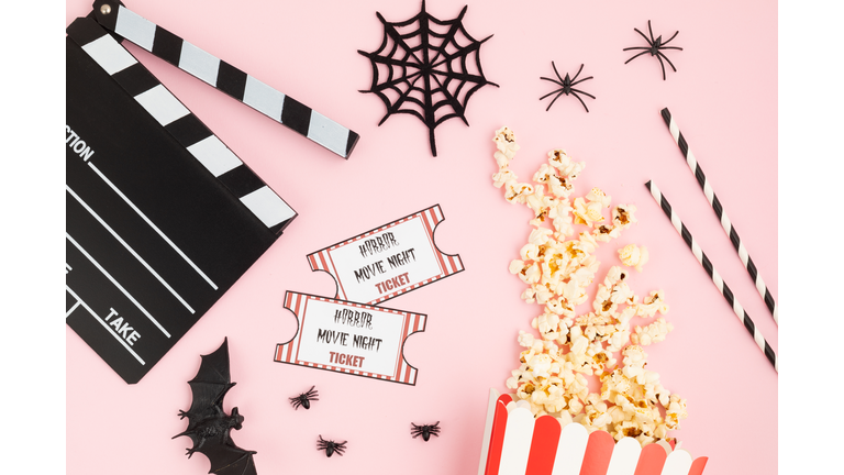 Movie clapperboard and halloween decoration over pink background