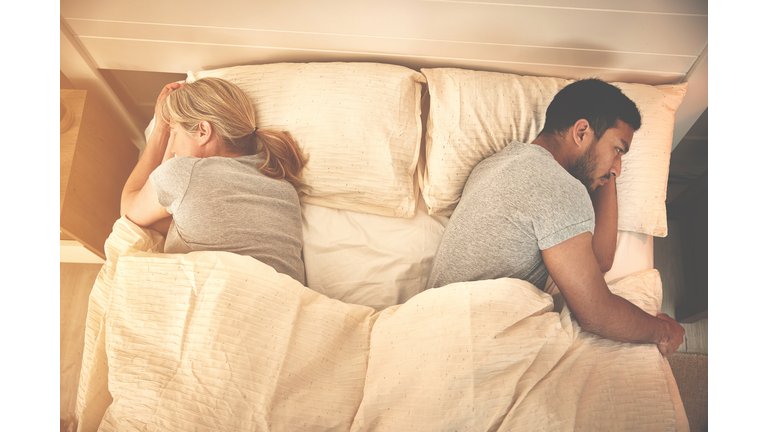 Above view of fighting couple lying in bed, facing away, backs to each other. Stubborn boyfriend ignoring girlfriend in bedroom at home. Man regretting hotel room affair with mature woman in morning