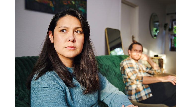 Cropped shot of an attractive young woman looking annoyed after arguing with her boyfriend who is sitting in the background