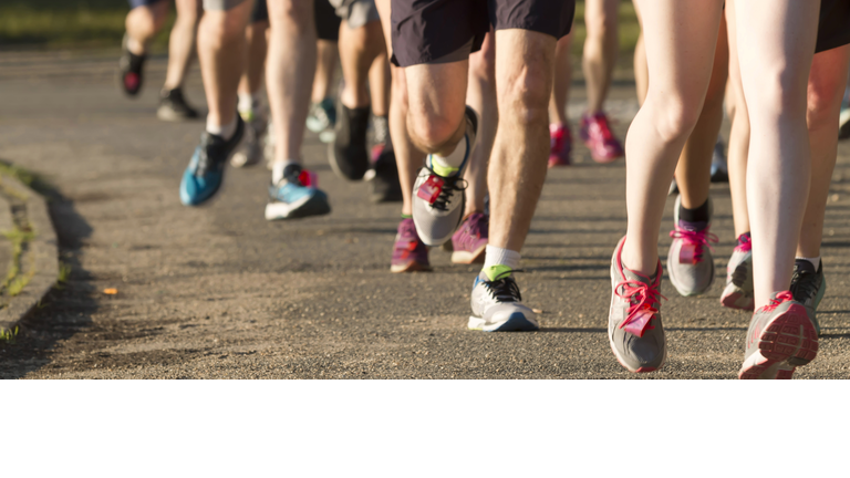 Legs of runners on a dirt path next to a lake