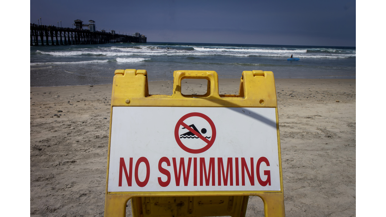 A sign at a beach stating No Swimming in red letters