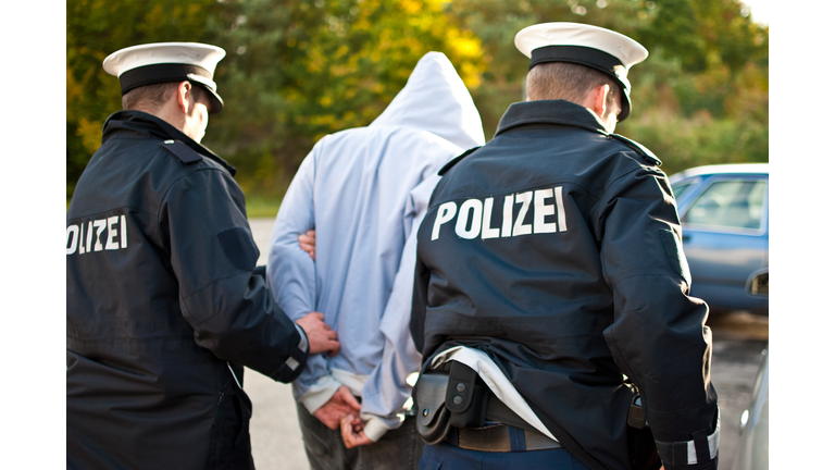 Two police officers are frogmarching a suspect