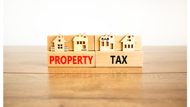 Property tax symbol. Concept words Property tax on wooden blocks. Beautiful wooden table white background. House models on wooden blocks. Business and property tax concept. Copy space.