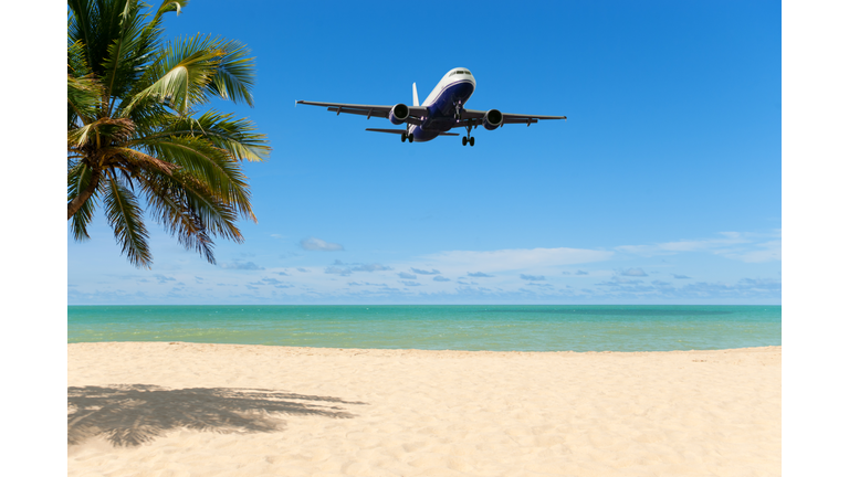 An airplane flying close over a tropical beach