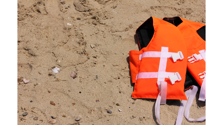 Orange life jacket lying on the sand. Safety on the water.