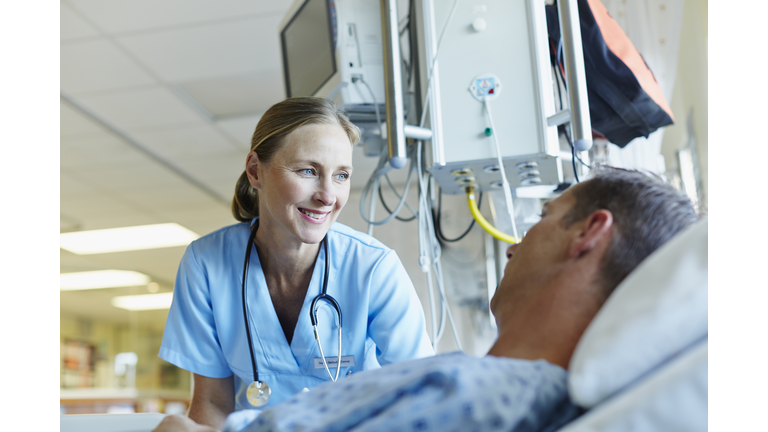 Smiling doctor looking at patient in hospital ward