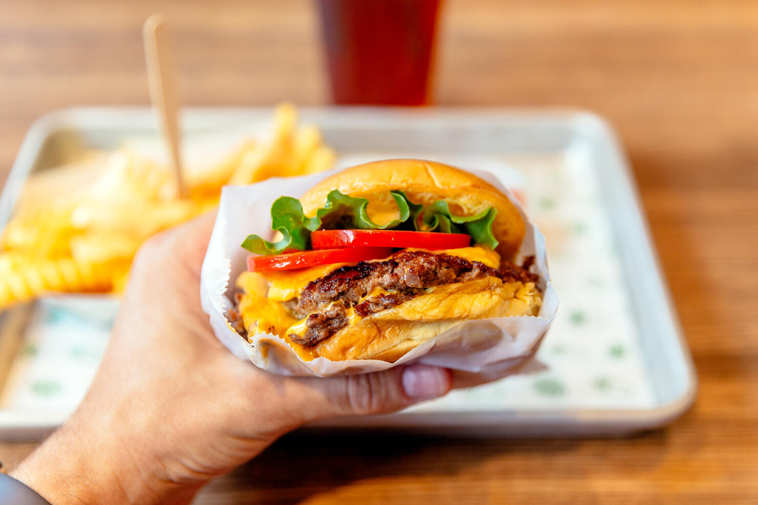 Man holding cheeseburger, close-up personal perspective view