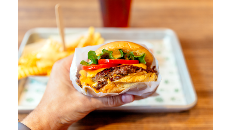 Man holding cheeseburger, close-up personal perspective view