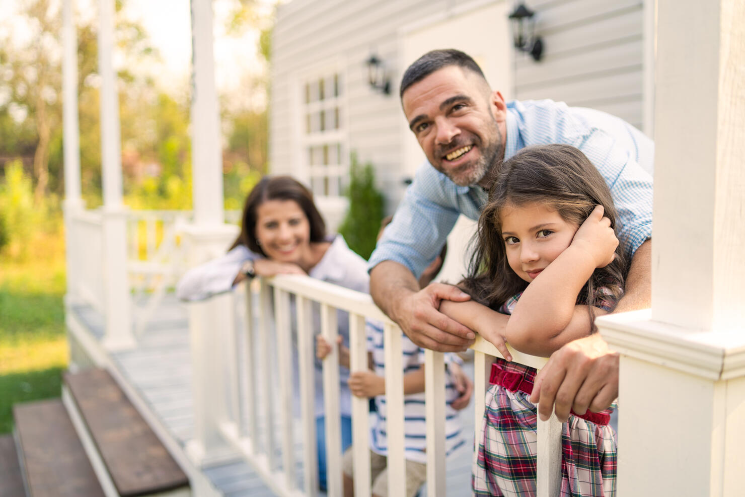 Two parents cuddling young daughter and baby son outdoors on the porch