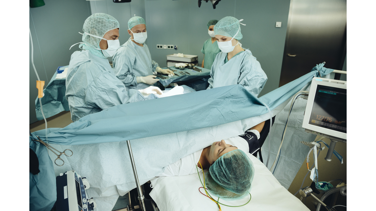 Team operating a woman on surgery table