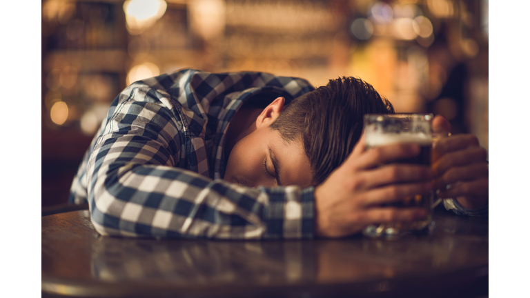 Young drunk man sleeping on the table in a bar.